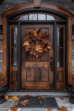 a front door with a wreath on it and autumn leaves in the ground next to it