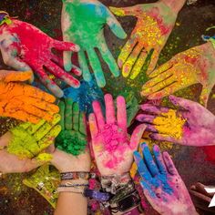 many hands are covered in colored powder and have their fingers painted with different colors on them