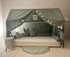 a child's tent bed with lights on the top and pillows underneath it, in a bedroom