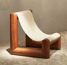 a chair made out of wood and white fabric on top of concrete floor next to wall