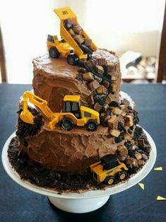 a three tiered chocolate cake with construction trucks on top