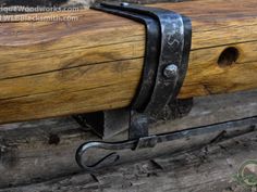 a pair of scissors hanging from the side of a wooden beam with metal straps on it