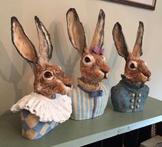 three rabbit statues sitting on top of a table