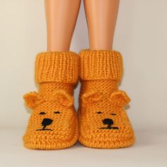 there is a pair of feet wearing knitted slippers with a bear face on them