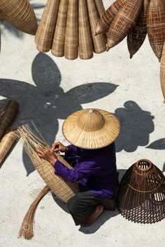 a person sitting on the ground next to some straw baskets and other items in front of them