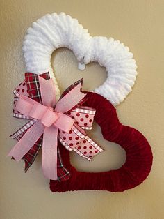 a heart shaped wreath hanging on the wall next to a red and white ribbon bow