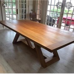 a large wooden table sitting on top of a hard wood floor next to sliding glass doors