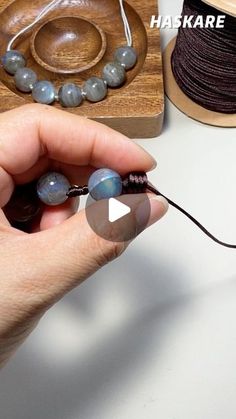 a person holding a bead in their hand with beads on the table next to it