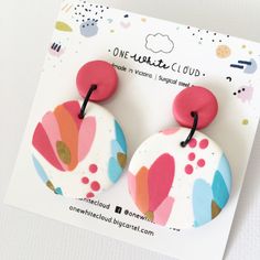 a pair of pink, blue and white earrings on a card