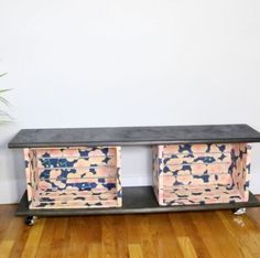 a black table with two pink and blue boxes on it's legs sitting on a hard wood floor