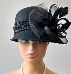 The featured hat is a  black colored wool winter dress hat.   The hat has a black and grey animal print band. The hat is decorated  with a black crinoline design of loops and swirls and black feathers. The combination of different textures  that makes this hat so charming. The brim can be worn curved up or down. The hat can be turned to different spots to create different looks. This hat can be worn as a winter Church Hat,an everyday winter hat,  a Downton Abbey hat, winter hat for warmth and style together and appropriate for all  winter special occasions. Brim:  Gradually widens from 1.5" --3" Rise:4.5" Size:22" This hat is made from 100" wool. Retro Hat, Church Hat, Retro Hats, Hat Wool, Dress Hat, Wool Winter, Church Hats, Winter Dress, Cloche Hat