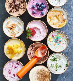 an assortment of desserts in small bowls with spoons on the side, including strawberries and blueberries