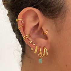 a woman wearing gold ear cuffs and piercings