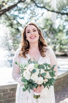 a woman in a white dress holding a bridal bouquet and smiling at the camera