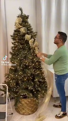 a man is decorating a christmas tree