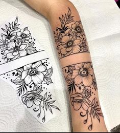 a woman's arm with black and white flowers on the left side of her arm