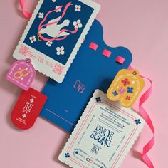 two tags are attached to the back of a blue and red envelope with pink ribbon