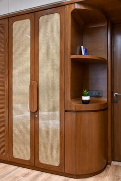 a wooden cabinet with glass doors and a plant in it's center, sitting on a hard wood floor