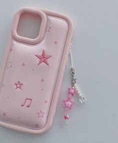 a pink cell phone case sitting on top of a white table next to a keychain