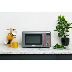 a microwave sitting on top of a counter next to a potted plant