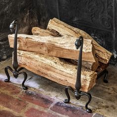 a bench made out of wood and wrought iron legs sitting on a brick floor next to a wall