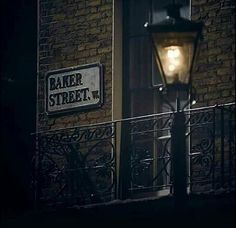 a street light sitting next to a brick building with a sign that reads baker street