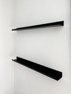 two black shelves are hanging on the wall