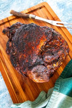 a piece of meat on a cutting board with a knife and fork next to it