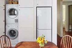 a vase with flowers on a table in front of a washer and dryer