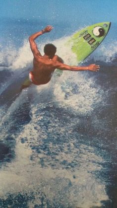 a man riding a surfboard on top of a wave in the ocean with his arms out