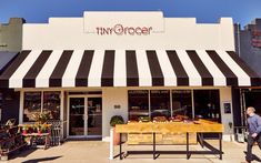 a man walking past a store front with a striped awning on it's roof