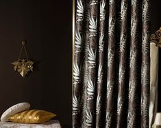 a bed sitting next to a window covered in curtains and gold pillows on top of it