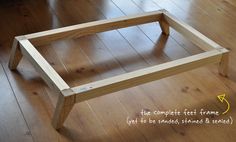 a wooden frame sitting on top of a hard wood floor next to a chair and table