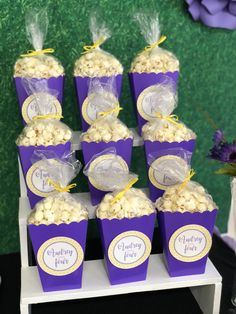 purple and yellow popcorn boxes with labels on them for guests to eat at a party