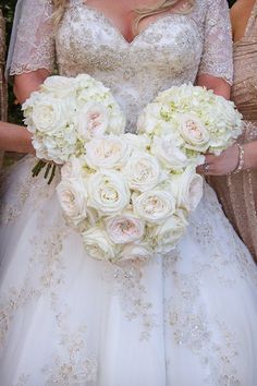 a bride holding a bouquet of white flowers in her hands with two other bridesmaids