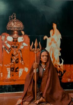 a woman sitting on the ground with a sceptacle in her hand and holding a staff