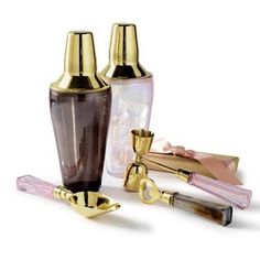 three different colored glass bottles with gold trimmings and one has a pink handle