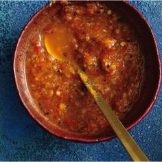 a red bowl filled with chili and an egg on top of it next to a spoon