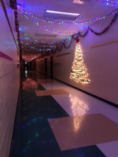 a hallway decorated with christmas lights and a lit up tree on the wall next to it