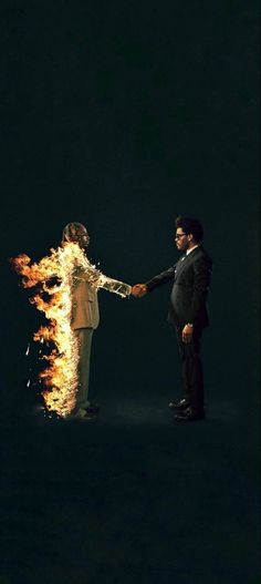 two people holding hands with fire in the background