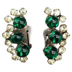 Dimensions: approx. 1.5" x 0.75" each Step back in time with our retro silver-tone clip-on earrings, featuring three cascading emerald crystal cabochons. Each earring is delicately accented with prong-set clear crystals, offering a sparkling contrast that catches the light beautifully. These vintage earrings are the perfect accessory for those who appreciate the elegance of a more stylish era. Add a touch of glamour to your ensemble with these exquisite pieces! Vintage Earrings, Clear Crystal, Prong Setting, Clip On Earrings, Silver Tone, Emerald, Jewelry Earrings, Sparkle, Crystals