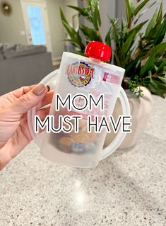 a mom must have bottle with her baby in it on the counter next to a potted plant