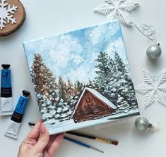 someone is painting a cabin in the snow with their paintbrushes and watercolors