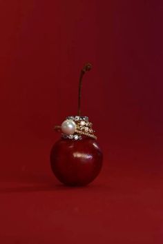 an apple with a ring on it sitting in front of a red background