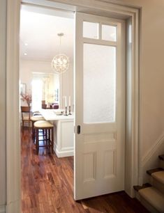 an open door leading to a kitchen and dining room with wood flooring on either side