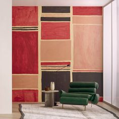 a green chair sitting in front of a red and black wall with squares on it