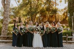 a group of women standing next to each other holding bouquets in their hands and smiling at the camera