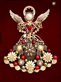 an angel brooch with pearls and other decorations on it's wings, sitting on a red velvet surface