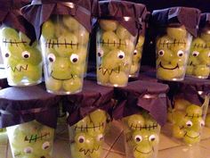 some green apples with faces painted on them and wrapped in purple ribbon, sitting next to each other