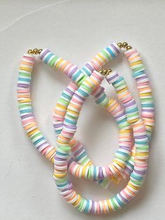 multicolored necklaces are arranged on a white surface with gold clasps and beads